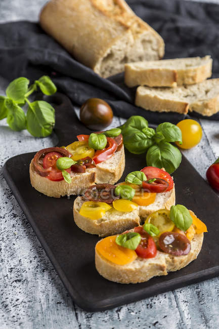 Bruschetta, ciabatta con pomodori multicolori e basilico — Foto stock