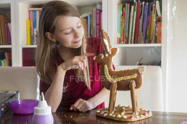 Menina sorridente com renas de gengibre caseiras em casa — Fotografia de Stock