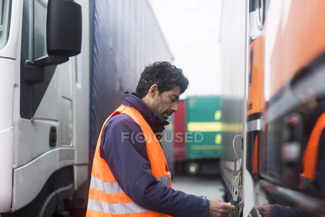 Чоловік в рефлекторному жилеті, який оглядає вантажівку — стокове фото