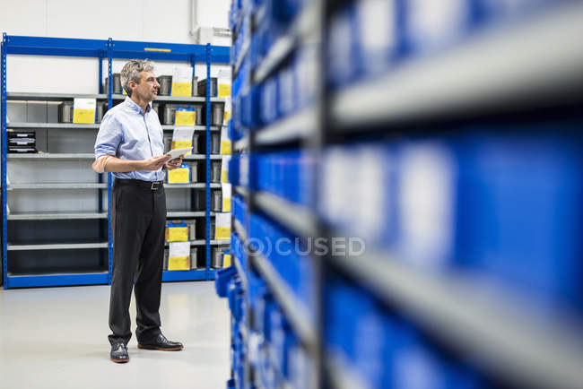Businessman using tablet in production hall — Stock Photo