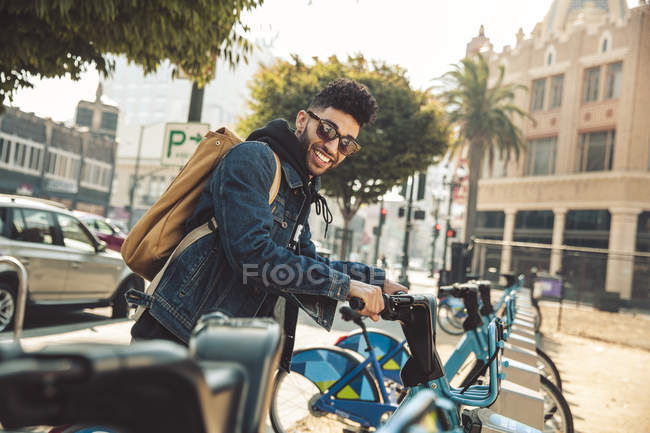 Stylish young man on the street with rental bike — Stock Photo