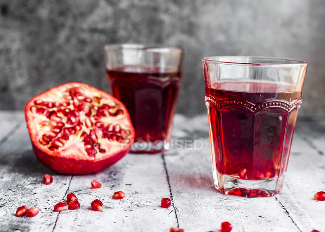Glasses of pomegranate juice and sliced pomegranate — Stock Photo