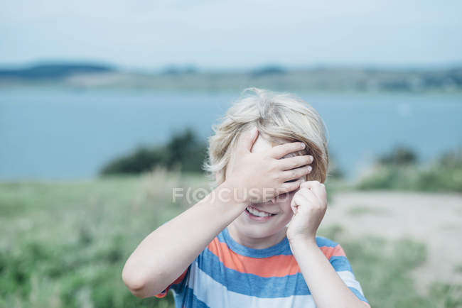 Sorridente ragazzo all'aperto che si copre gli occhi — Foto stock