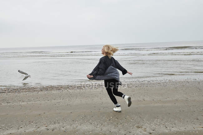 Pays-Bas, jeune femme blonde heureuse courant sur la plage — Photo de stock