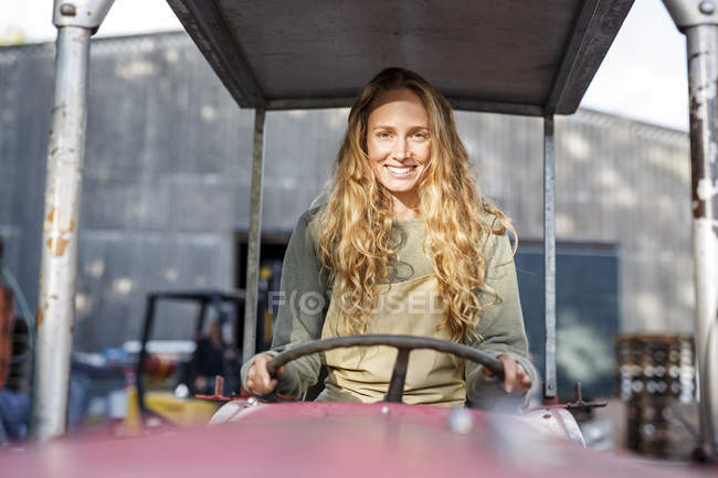 Портрет улыбающейся женщины за рулем трактора — стоковое фото