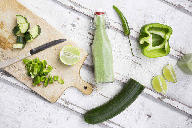Скляна пляшка домашнього зеленого Gazpacho і інгредієнтів — стокове фото