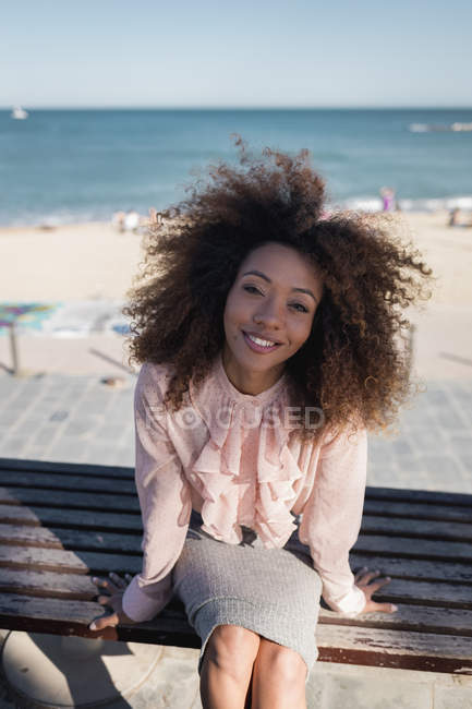 Portrait of smiling beautiful young woman with afro hairdo sitting on a bench at the beach — tourism, Incidental People - Stock Photo | #263845762 Portrait of smiling beautiful young woman with afro hairdo sitting on a bench at the beach — tourism, Incidental People - Stock Photo | #263845762