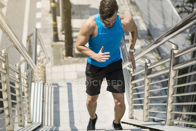 Man in blue fitness shirt running upstairs in city — Stock Photo