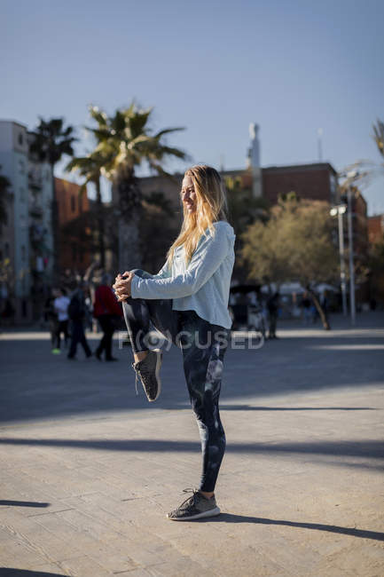 Spanien, Barcelona, Frau streckt Bein auf Strandpromenade — Stockfoto