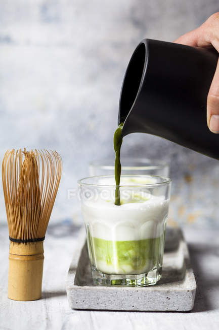 Matcha Latte, derramando chá matcha em um copo — Fotografia de Stock