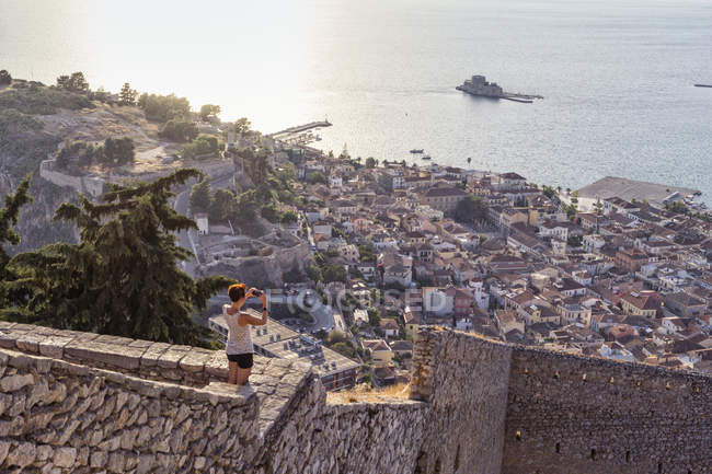 Grécia, Peloponeso, Argolis, Náuplia, Golfo Argólico, mulher fotografando vista para o Castelo de Bourtzi — Fotografia de Stock