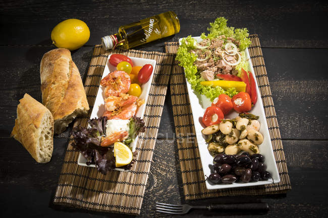 Antipasti, tuna, salad, filled paprika, white beans, black olive, shrimp, sour cream, tomato and white bread — Stock Photo