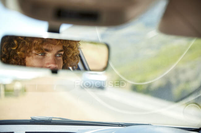 Joven conduciendo coche, espejo retrovisor, espejo - foto de stock