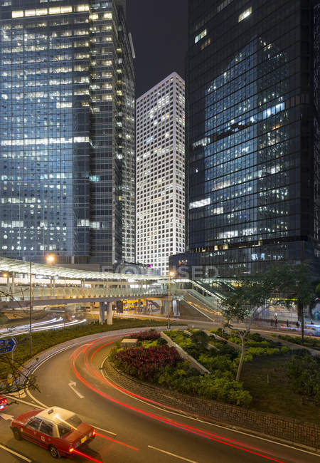 China, Hong Kong, edificios de gran altura y taxi por la noche - foto de stock