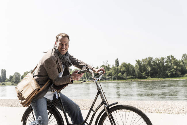 Uomo maturo con bicicletta utilizzando smartphone a riva del Reno — Foto stock