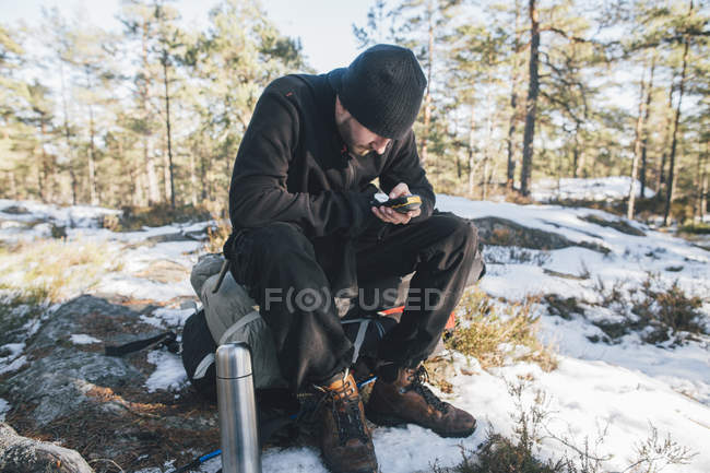 Suecia, Sodermanland, mochilero descansando en el paisaje remoto en invierno utilizando rastreador GPS - foto de stock