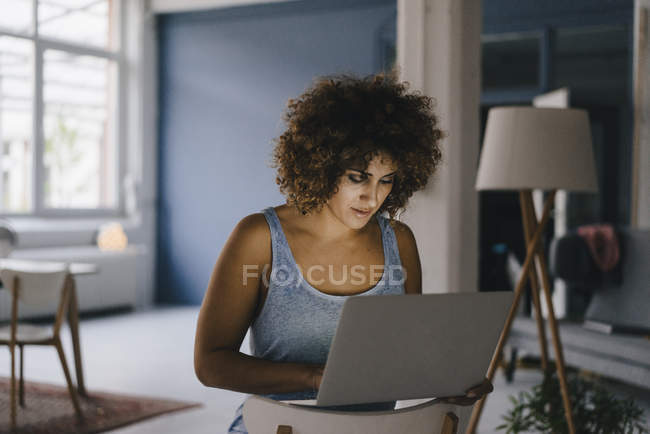 Mujer que trabaja horas extras en su negocio de puesta en marcha, utilizando el ordenador portátil - foto de stock