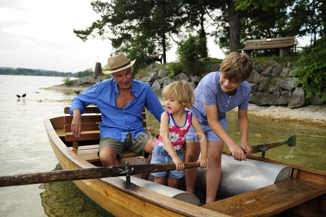 Germany, Bavaria, Murnau, grandfather with grandson and granddaughter in rowing boat — Stock Photo