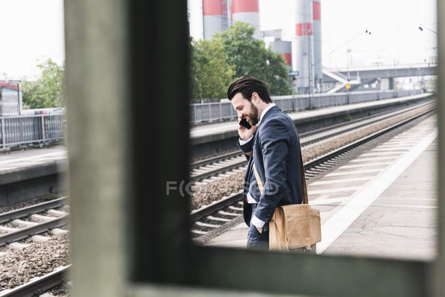 Uomo d'affari al cellulare in piedi sulla piattaforma — Foto stock