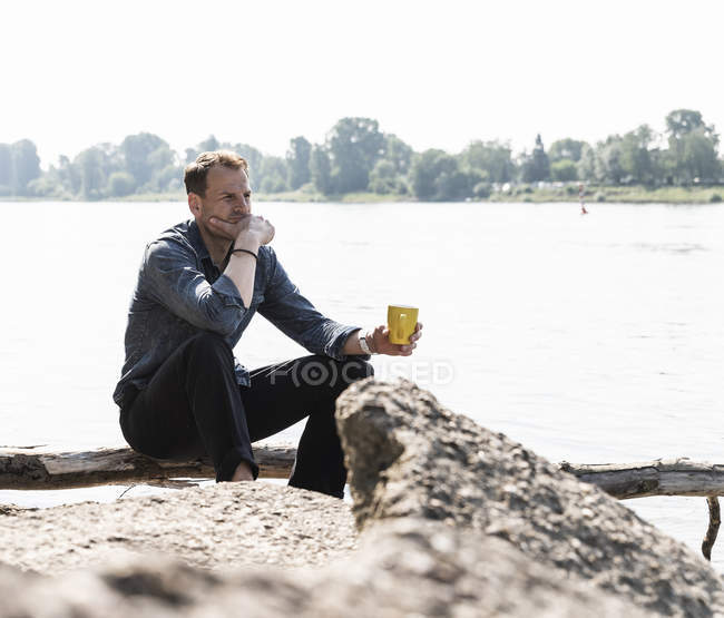 Зрелый человек, сидящий на берегу Рейна, смотрит на расстояние — стоковое фото