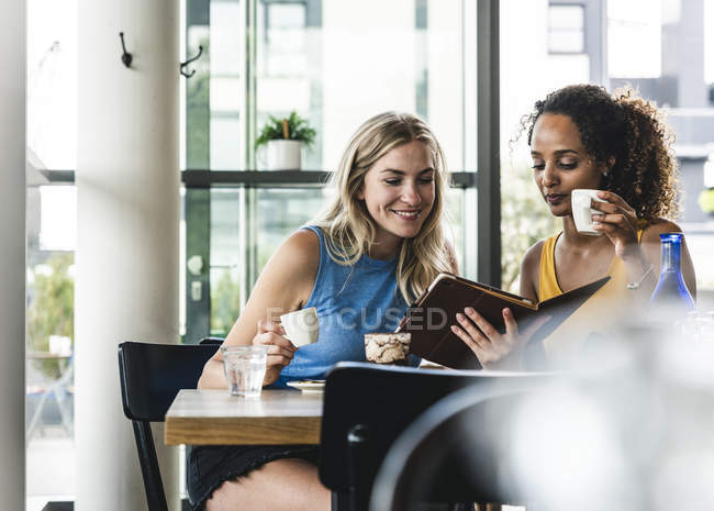 Best friends meeting in cafe, talking and sharing news, using digital tablet — Stock Photo