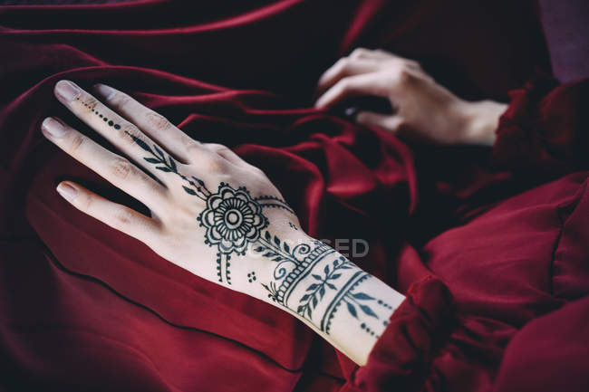 Main de femme avec tatouage au henné sur tissu rouge — Photo de stock