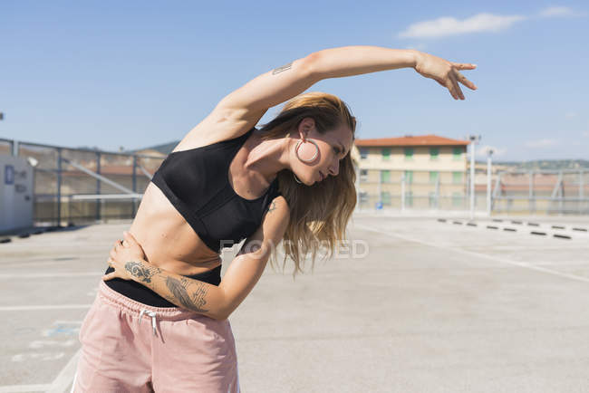 Tatuado jovem mulher fazendo exercícios de alongamento — Fotografia de Stock