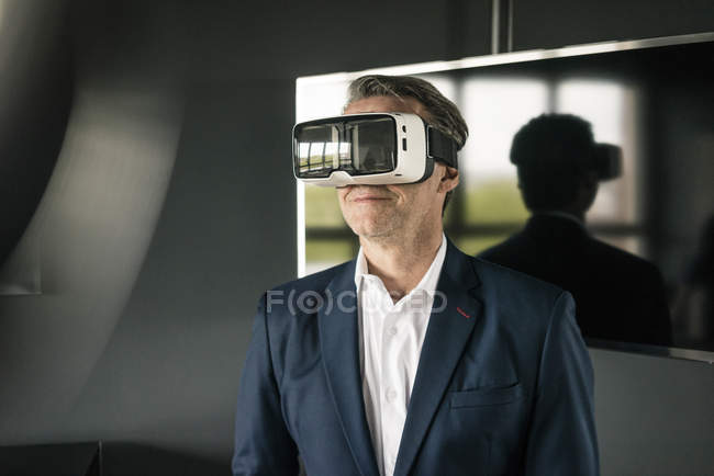 Mature businessman wearing VR glasses in office — Stock Photo
