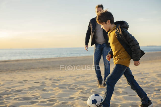 Padre e figlio giocano a calcio sulla spiaggia — Foto stock