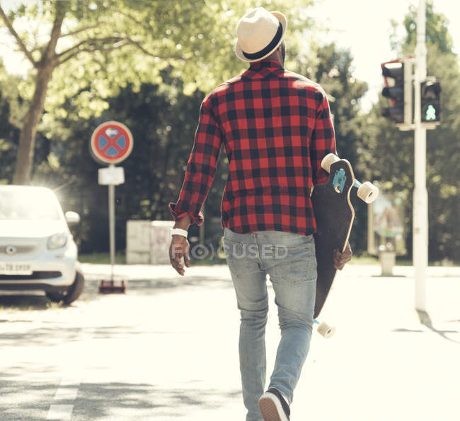 Cooler junger Mann mit Skateboard in der Stadt unterwegs, — Stockfoto