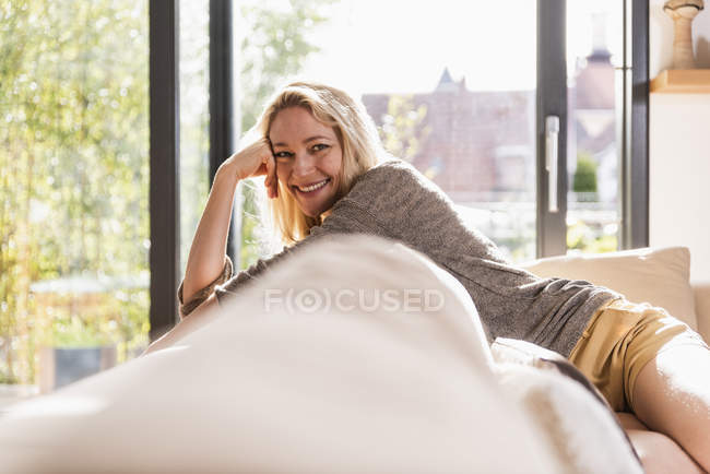 Портрет щасливої зрілої жінки, яка відпочиває вдома на дивані. — стокове фото
