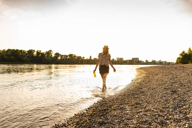 Giovane donna che cammina a piedi nudi sul lungofiume la sera — Foto stock