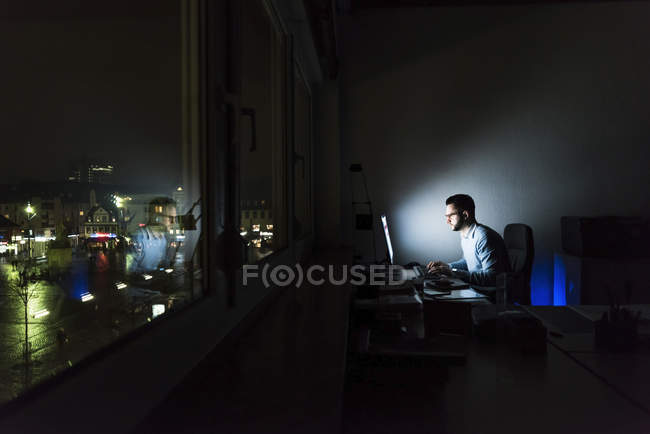 Geschäftsmann arbeitet im dunklen Büro am Computer — Stockfoto