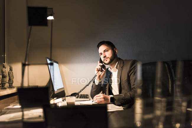 Empresario al teléfono en la oficina por la noche - foto de stock