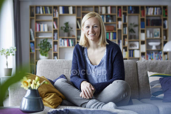Femme relaxante à la maison, assise sur le canapé — Photo de stock