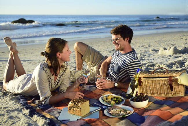 Happy couple having a picnic on the beach — Stock Photo