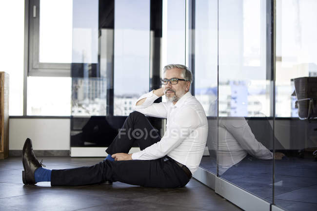 Empresário sentado no chão no escritório — Fotografia de Stock