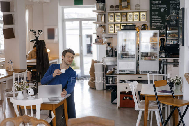 Mann sitzt mit Laptop am Tisch in Café — Stockfoto