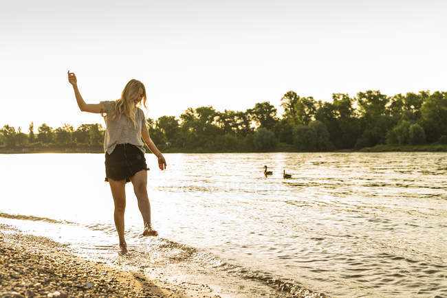 Giovane donna che cammina a piedi nudi sul lungofiume — Foto stock