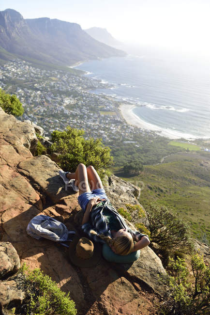 South Africa, Cape Town, woman lying on rock during hiking trip to Lion 's Head — стоковое фото