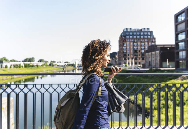 Jeune femme d'affaires marchant sur le pont, parlant au téléphone — Photo de stock