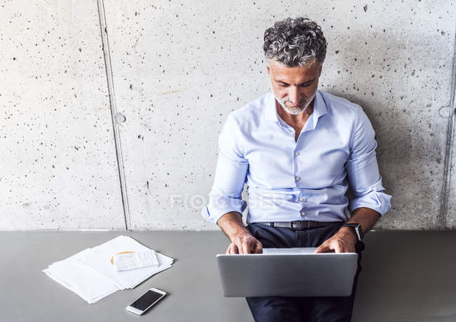 Mature businessman sitting on floor and using laptop — Stock Photo