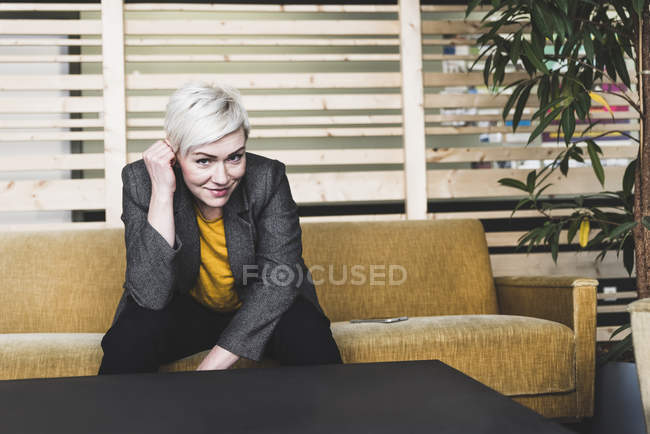 Portrait of smiling casual businesswoman sitting on couch in lounge — Stock Photo