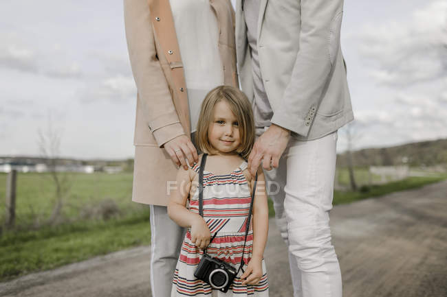 Porträt eines lächelnden kleinen Mädchens mit Eltern, die hinter ihr stehen — Stockfoto