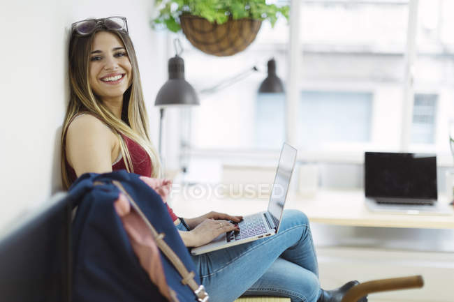 Smiling casual young woman using laptop in the office — Stock Photo