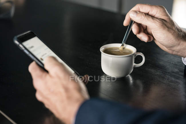 Close-up of businessman with cup of coffee using cell phone — Stock Photo