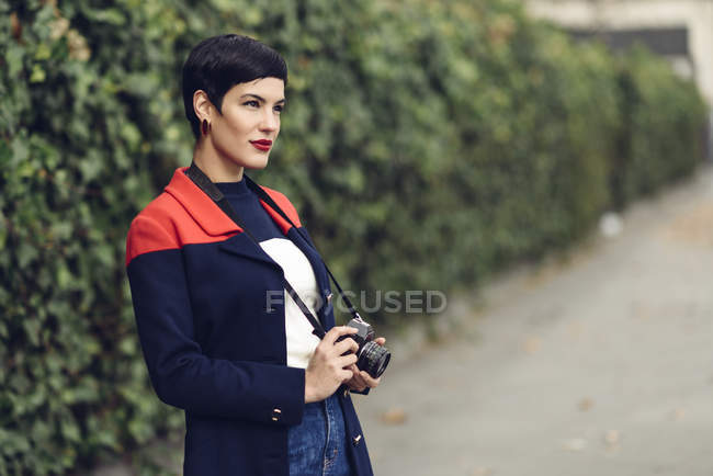 Portrait of fashionable young woman with camera — Stock Photo