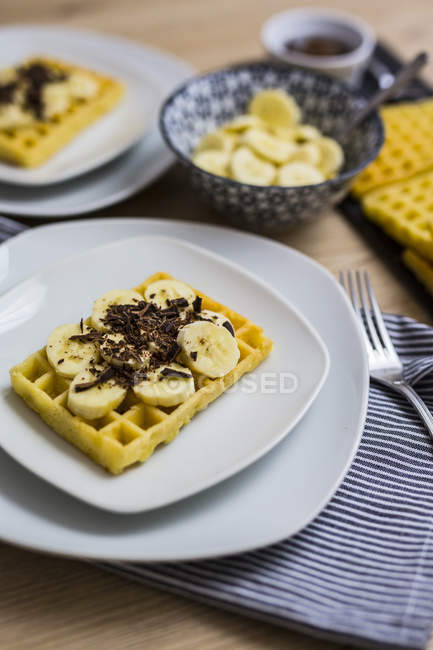 Waffle garnished with banana and chocolate shaving on plate — Stock Photo