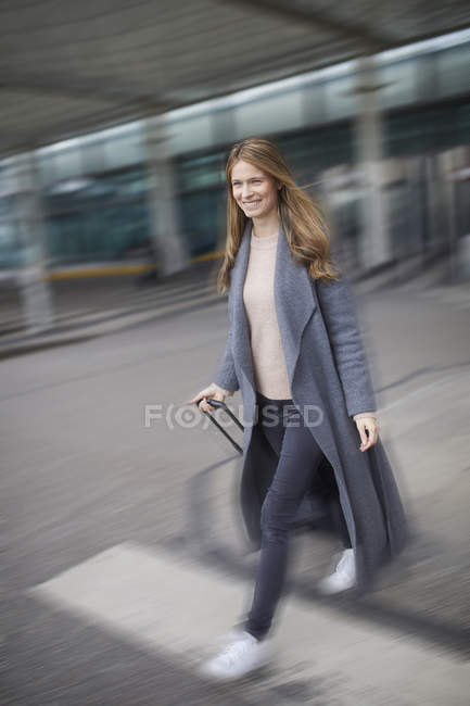 Уверенная деловая женщина тащит чемодан в аэропорт — стоковое фото