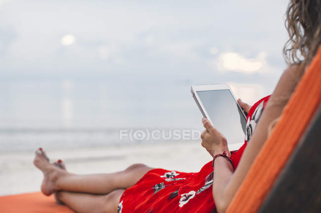 Thailand, Koh Phangan, woman sitting on sunlounger using digital tablet on the beach — Stock Photo